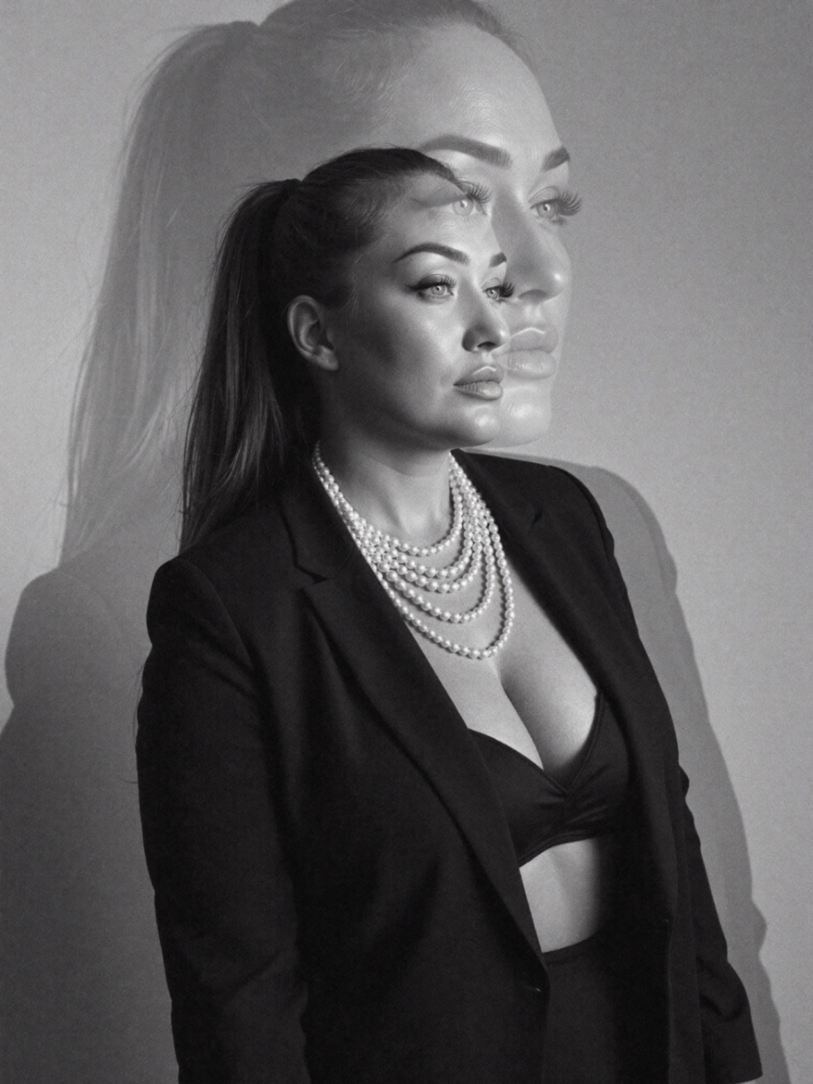 Portrait of Katie in a black blazer with pearls